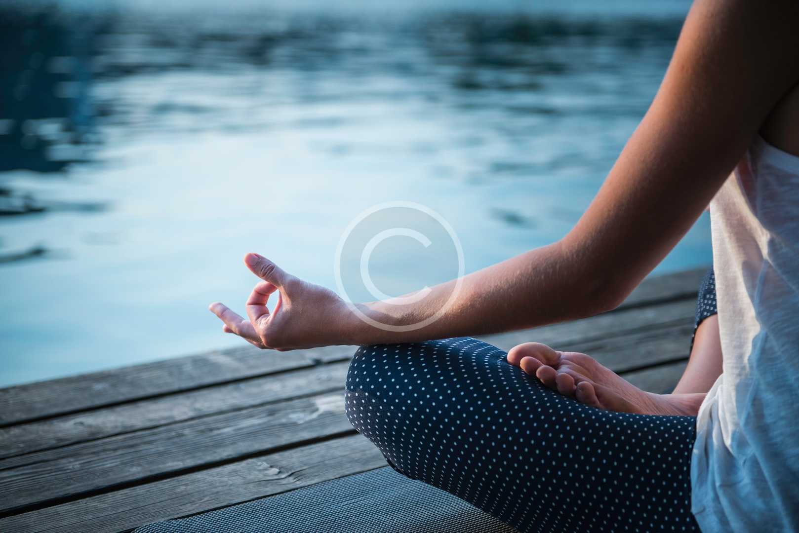Meditating by the lake, sitting in lotus position, relaxed, selective focus